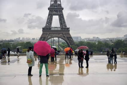 Des spectateurs contemplent la Tour Eiffel sous leur parapluie